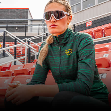 A softball player wearing a black and green pullover