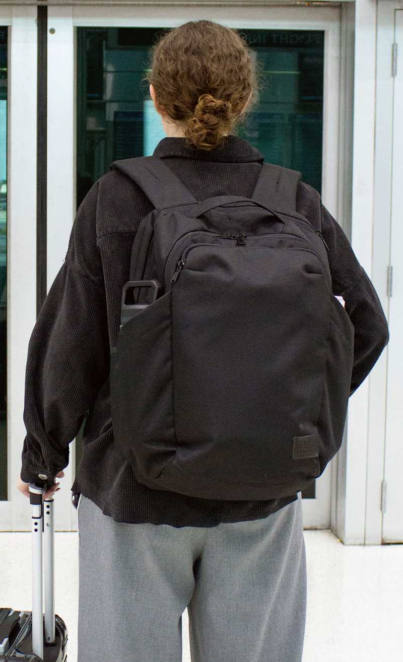 Female model in black wearing the Commuter Backpack