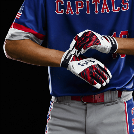 A baseball player putting on a pair of white, black and red batting gloves