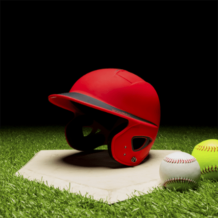 A red batting helmet on a plate next to two baseballs