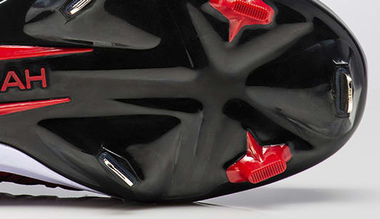 The red and black sole of baseball shoe with metal cleats