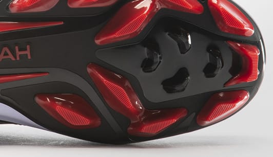 The red and black sole of baseball shoe with molded cleats